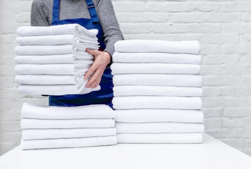 worker hands hold lot white towels laundry hotel white background